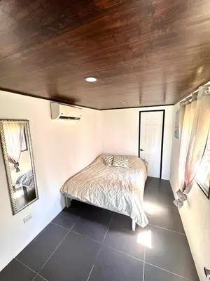 a small bedroom with a bed and a mirror at Mini House 2 in Uvita