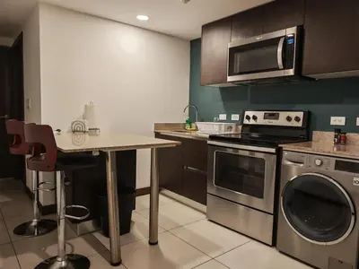 a kitchen with a table and a stove and a microwave at 1702 Torres los Yoses cozy apartment on the 17th floor with balcony in San José