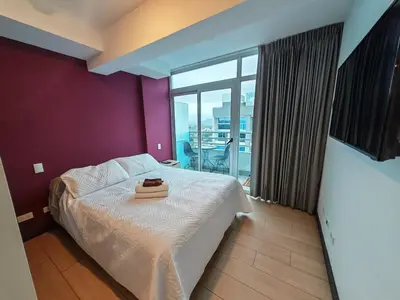 a bedroom with a bed with a purple wall at 1702 Torres los Yoses cozy apartment on the 17th floor with balcony in San José