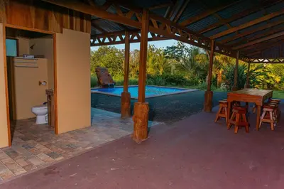 a pavilion with a table and chairs and a pool at Casa Los Chorros in Agua Azul