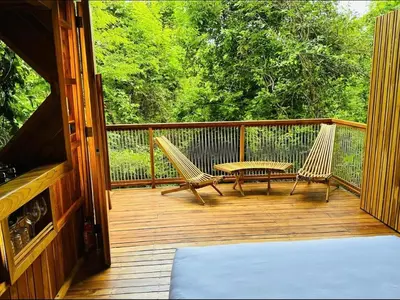 a porch with two chairs and a table on it at Pura selva tree house in Tamarindo