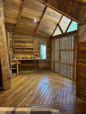 an empty room with wooden flooring and a large window at Pura selva tree house in Tamarindo