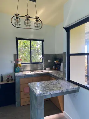 a kitchen with a marble counter top and a window at Hawk Hope Tiny House with Sunset Views in Bagaces