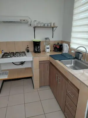 a small kitchen with a stove and a sink at Sunset House Herradura in Herradura