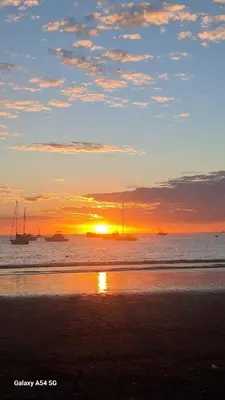 a sunset on the beach with boats in the water at Sunset House Herradura in Herradura