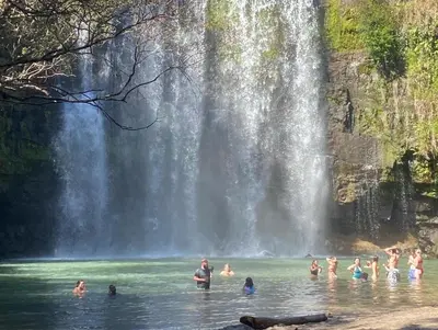 a group of people in the water in front of a waterfall at Fun in the sun, ground floor, 2 Bedroom, with pool, close to ocean in Coco