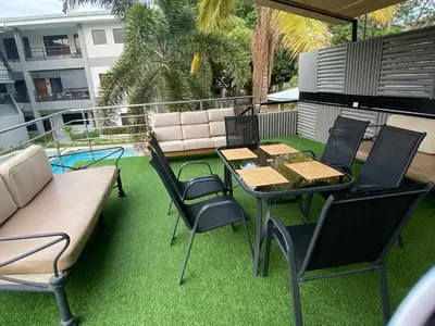 a patio with a table and chairs on the grass at Fun in the sun, ground floor, 2 Bedroom, with pool, close to ocean in Coco
