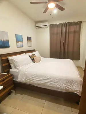 a bedroom with a white bed with a ceiling fan at Fun in the sun, ground floor, 2 Bedroom, with pool, close to ocean in Coco