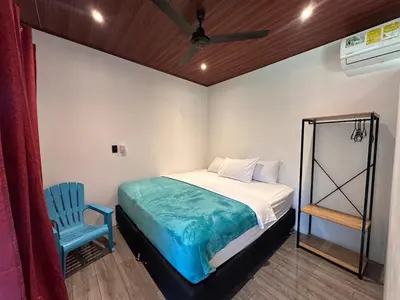 a bedroom with a bed and a blue chair at Hospedaje Quepos Tardes Doradas in Quepos