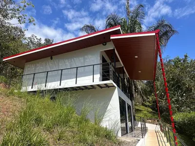 a building on a hill with a red pole at Hospedaje Quepos Tardes Doradas in Quepos