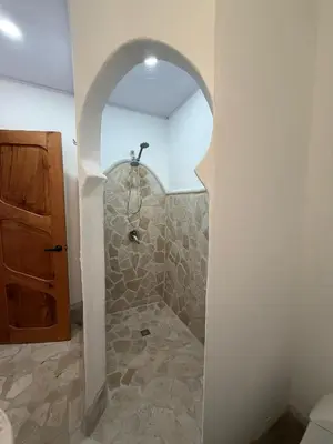 a bathroom with a shower with a stone floor at Villa Sol Kite House in La Cruz