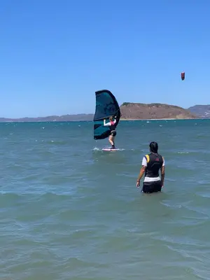 a couple of people in the water with a windsurfer at Villa Sol Kite House in La Cruz