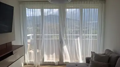 a living room with a large window with white curtains at Secure & Confortable Apartment with green spaces in San Rafael
