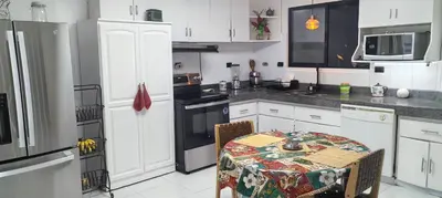 a kitchen with white cabinets and a table with a table cloth at Casagerardine in Alajuela City