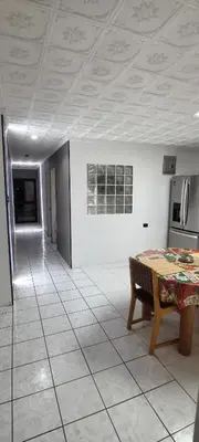 a living room with a table and a kitchen at Casagerardine in Alajuela City
