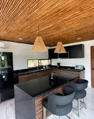 a kitchen with black counters and a wooden ceiling at Casa Ángel playa grande in Cuajiniquil