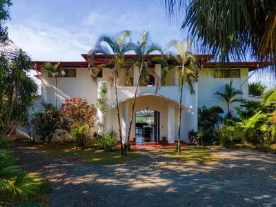 a white house with palm trees in front of it at Casa Castillo in Quepos