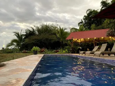 a swimming pool with chairs and a pavilion at Casa Castillo in Quepos
