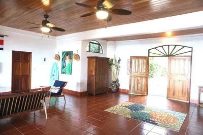 a living room with a ceiling fan and a table at Casa Castillo in Quepos