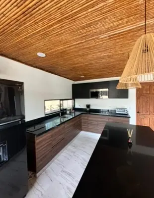 a kitchen with black counters and a wooden ceiling at Casa Ángel in Matapalo