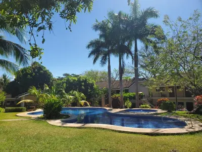 a swimming pool in front of a house with palm trees at Sea Heaven Ground Floor Studio in Coco