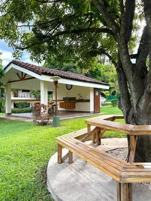 a wooden bench sitting under a tree in a park at Sea Heaven Ground Floor Studio in Coco