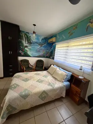 a bedroom with a bed and a painting on the wall at Sea Heaven Ground Floor Studio in Coco
