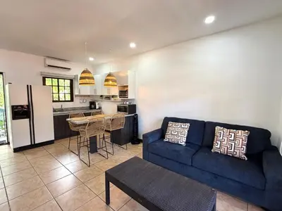 a living room with a blue couch and a kitchen at Plaza Colonial Second Floor One Bedroom Unit in Coco