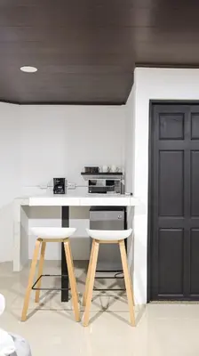 a kitchen with a white counter and two stools at Palma Roots in Jacó