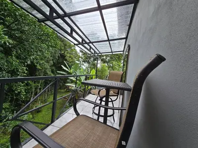 a balcony with a table and a chair on it at SeStudio Lodge in Nuevo Arenal with Jungle Views in Nuevo Arenal
