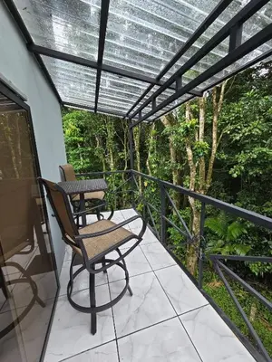 a patio with a table and chairs on a balcony at SeStudio Lodge in Nuevo Arenal with Jungle Views in Nuevo Arenal