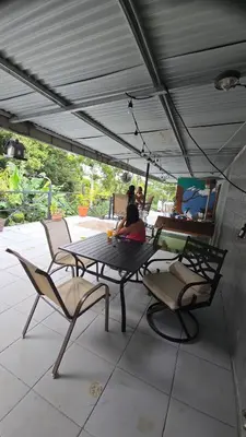 a woman sitting at a table under a patio umbrella at SeStudio Lodge in Nuevo Arenal with Jungle Views in Nuevo Arenal