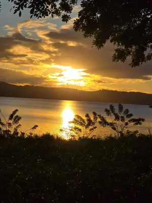 a sunset over a body of water with the sun setting at Stay at Alexas Nature House in Nuevo Arenal