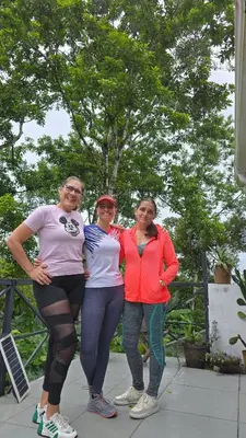 three women standing next to each other in front of a tree at Stay at Alexas Nature House in Nuevo Arenal