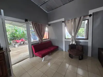 a living room with a red couch and windows at Stay at Alexas Nature House in Nuevo Arenal
