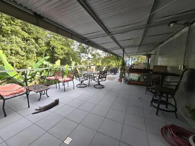 a patio with tables and chairs and a cat laying on the floor at Stay at Alexas Nature House in Nuevo Arenal