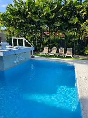 a blue swimming pool with two chairs and trees at Arenal Igloo Private House in Fortuna