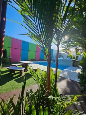 a colorful building with a pool and a palm tree at Arenal Igloo Private House in Fortuna