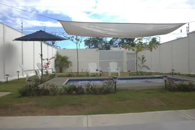 a patio with an umbrella and chairs and a pool at Villa Libélula in Quepos