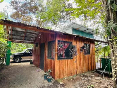 a wooden house with a car parked in front of it at Mayra Campground in Savegre