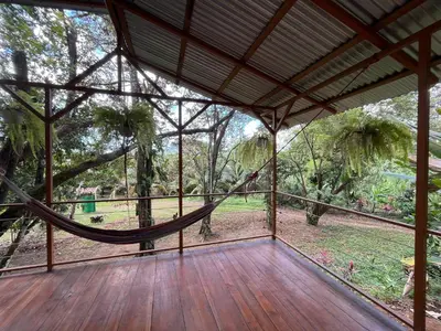 a screened porch with a hammock in a forest at Mayra Campground in Savegre