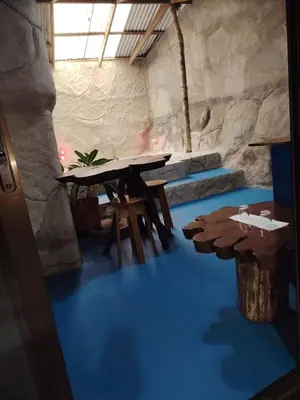 a room with a table and two logs on the floor at Vértice Blue Mountain Lodge la cueva de la montaña in San Lorenzo
