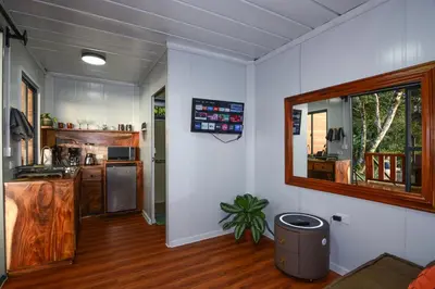 a kitchen with white walls and wooden floors at Cabaña Los Lirios in Monteverde Costa Rica