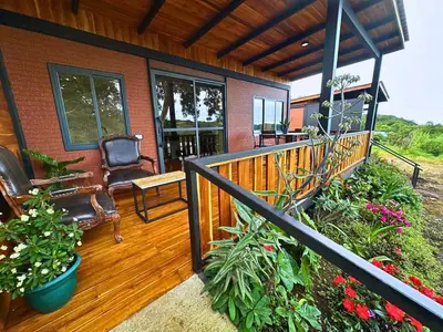 a porch of a house with a chair and flowers at Cabaña Los Lirios 2 in Monteverde Costa Rica