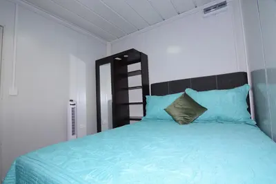 a bedroom with a bed with blue sheets and a mirror at Cabaña Los Lirios 2 in Monteverde Costa Rica