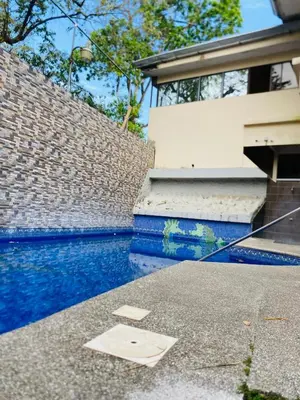 a house with a swimming pool next to a brick wall at Apartamentos Santa Teresita in Santa Teresa Beach