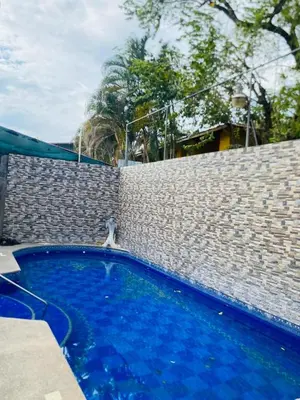 a blue swimming pool next to a brick wall at Apartamentos Santa Teresita in Santa Teresa Beach