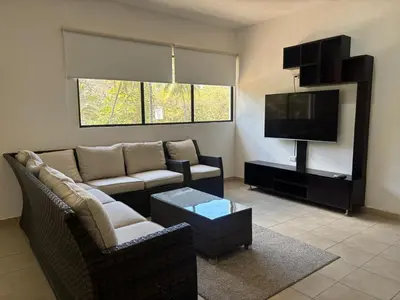 a living room with a couch and a flat screen tv at Apartamentos Santa Teresita in Santa Teresa Beach