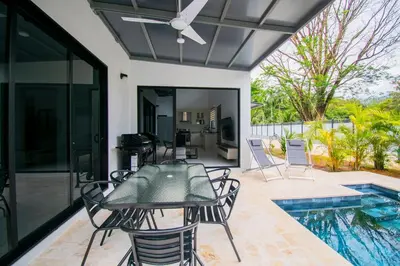 a patio with a table and chairs and a swimming pool at 5 min walk to Uvita beach, pool, 3 bdr, AC! in Uvita