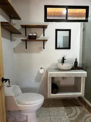 a bathroom with a white toilet and a sink at Casa Bahia Heliconia in Uvita